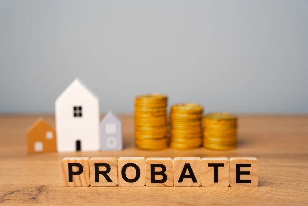 Real estate that is part of a deceased person's estate and managed or distributed through the probate process. Wooden blocks Probate and miniature houses.